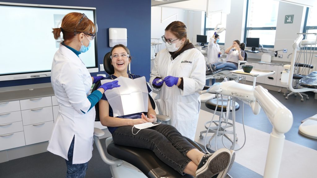 Professeure et étudiantes simulant des soins dentaires